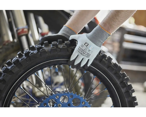 Gebol Arbeitshandschuhe Master Flex Cool und Touch beim Festhalten eines Motorradreifens mit Stollenprofil in einer Werkstatt.