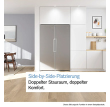 Side-by-Side Kühlschrank aus Edelstahl in einer modernen, hellen Küche mit weißen Schränken und hellem Holzboden.