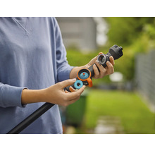 Eine Person setzt einen blauen Dichtungsring oder Filter in einen schwarzen Gießstab für die Gartenbewässerung ein.