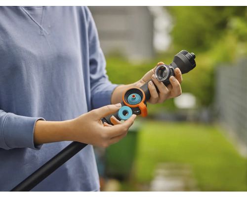 Eine Person setzt einen blauen Dichtungsring oder Filter in einen schwarzen Gießstab für die Gartenbewässerung ein.