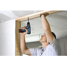 Person verwendet einen Bosch Akku-Bohrschrauber zur Bearbeitung eines Holzrahmens bei einer Renovierung.
