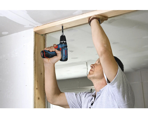 Person verwendet einen Bosch Akku-Bohrschrauber zur Bearbeitung eines Holzrahmens bei einer Renovierung.