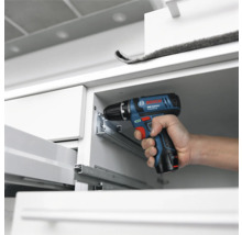 Bosch Professional Akku-Bohrschrauber bei der Montage von Metall-Schubladenschienen in einem weißen Schrank.