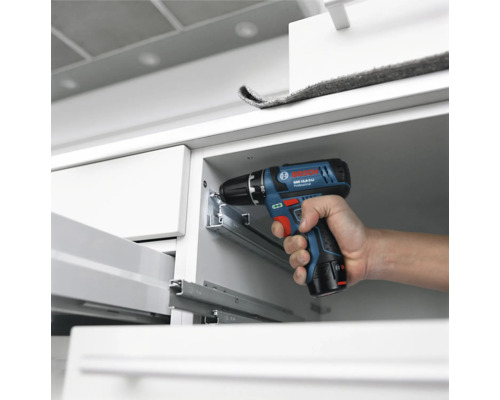 Bosch Professional Akku-Bohrschrauber bei der Montage von Metall-Schubladenschienen in einem weißen Schrank.