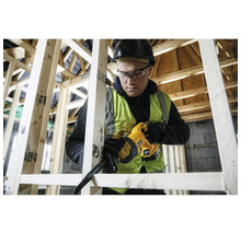 Handwerker mit Schutzhelm verwendet eine DeWalt Akku-Säbelsäge zum Sägen von Holzlatten in einem Holzständerbau auf einer Baustelle.