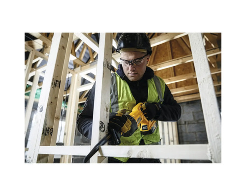 Handwerker mit Schutzhelm verwendet eine DeWalt Akku-Säbelsäge zum Sägen von Holzlatten in einem Holzständerbau auf einer Baustelle.