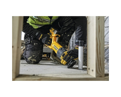 Handwerker nutzt eine batteriebetriebene DeWalt Säbelsäge zum Schneiden eines Kunststoffrohrs neben Holzständerwerk auf einer hellen Baustelle.