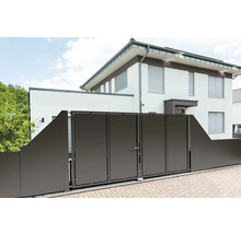 Modernes anthrazitfarbenes Einfahrtstor und Sichtschutzzaun vor einem weißen Wohnhaus mit gepflasterter Garagenzufahrt.