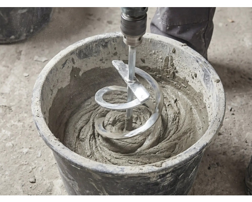 Ein Wendelrührer rührt grauen Mörtel in einem schwarzen Baueimer an.