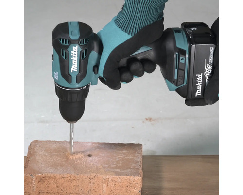 Makita Akku-Bohrschrauber 18 Volt mit eingesetztem Steinbohrer beim Bohren in einen Ziegelstein.