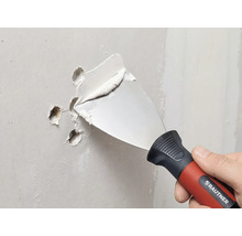 RAUTNER Malerspachtel füllt Löcher in einer Wand mit Spachtelmasse.
