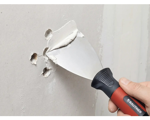 RAUTNER Malerspachtel füllt Löcher in einer Wand mit Spachtelmasse.