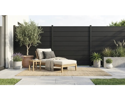 Moderner Sichtschutzzaun aus anthrazitfarbenen Lamellen auf einer Terrasse mit Holzliege und verschiedenen Topfpflanzen.
