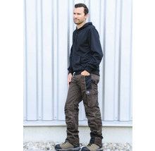 Mann in brauner Arbeitshose mit verstärkten Knien und Taschen, kombiniert mit schwarzem Kapuzenpullover und Arbeitsschuhen.