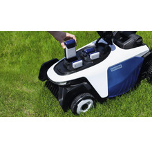 Eine Hand setzt einen Akku in einen weiß-blauen Easysurge Mähroboter auf einer grünen Rasenfläche ein.