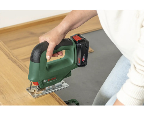 Eine Person schneidet mit einer Bosch Akku-Stichsäge EasySaw 18V-70 ein Stück Laminatboden.