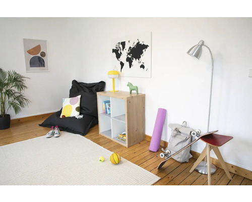 Heller Raum mit Holzboden, Holzregal, schwarzem Sitzsack, silberner Stehleuchte und hellem Teppich.