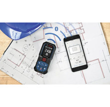 Bosch Laser-Entfernungsmesser mit Bluetooth-Verbindung zu einer Smartphone-App auf einem Bauplan.