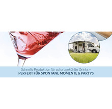 Nahaufnahme eines Cocktailglases mit Eiswürfeln und ein Wohnmobil auf einer Wiese für Camping und Feiern.