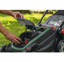 Einsetzen eines Akkus in das Batteriefach eines Akku-Rasenmähers im Garten.