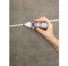 Hand trägt Lugato Fugen-Perle Fugenschutz auf eine Fliesenfuge auf.