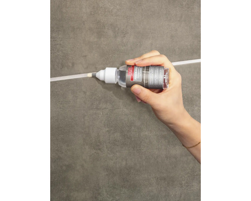 Hand trägt Lugato Fugen-Perle Fugenschutz auf eine Fliesenfuge auf.