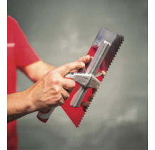 Eine Person hält eine Zahnkelle aus Edelstahl mit einem ergonomischen Griff.