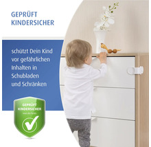 Ein Kleinkind steht neben einer Kommode, die mit einer geprüften Kindersicherung für Schubladen und Schränke gesichert ist.