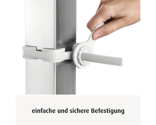 Hand zieht eine weiße Kunststoffbefestigung mit einem Montageschlüssel an einem quadratischen Metallpfosten fest.