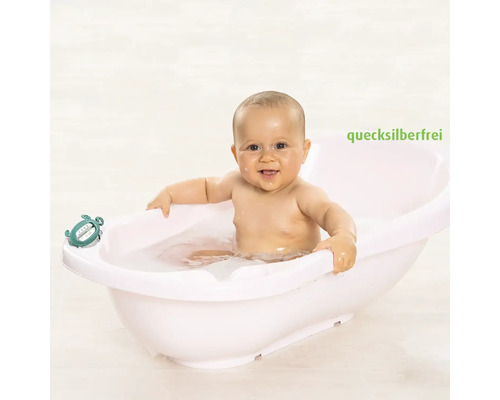 Baby in einer weißen Babywanne mit einem Badethermometer, quecksilberfrei.
