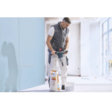 Handwerker rührt mit einem elektrischen Rührwerk Spachtelmasse in einem Eimer an, neben einem Sack Knauf Allround.