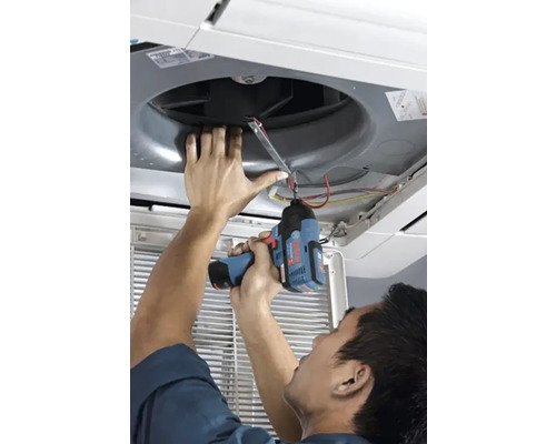Eine Person nutzt einen Bosch Akku-Schlagschrauber zur Montage oder Reparatur einer Deckenklimaanlage.