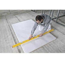 Handwerker schneidet eine Gipskartonplatte mit einem Cuttermesser und einer Wasserwaage auf einer Baustelle.