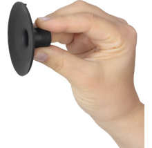 Hand hält einen kleinen schwarzen Saugnapf aus Gummi zwischen Daumen und Zeigefinger.
