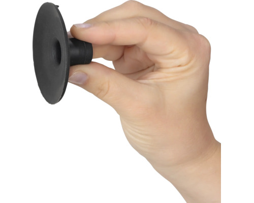 Hand hält einen kleinen schwarzen Saugnapf aus Gummi zwischen Daumen und Zeigefinger.