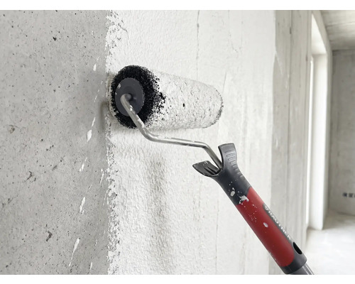 Rautner Farbroller trägt Farbe auf eine strukturierte Betonwand auf.