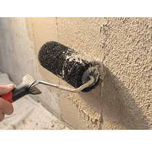 Strukturwalze beim Auftragen von Rollputz auf eine raue Wand.