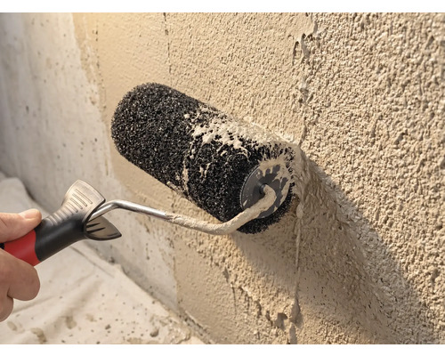 Strukturwalze beim Auftragen von Rollputz auf eine raue Wand.
