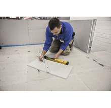 Handwerker markiert Gipskartonplatte mit Bleistift und Metalllineal neben einer digitalen Wasserwaage.