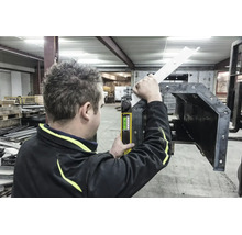 Eine Person verwendet einen digitalen Winkelmesser zum Messen eines Metallwerkstücks in einer hellen Werkstatt.