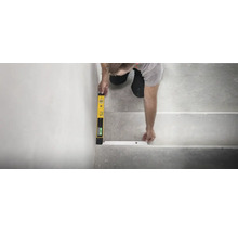 Eine Person richtet mit einer digitalen Wasserwaage ein Treppenkantenprofil auf einer Betontreppe aus.