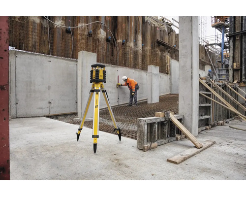 Stabila Rotationslaser auf Stativ auf einer Baustelle mit einem Bauarbeiter, der Messungen an einer Betonwand vornimmt.