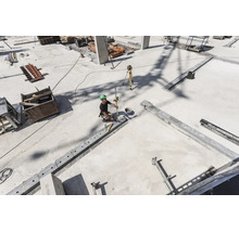 Bauarbeiter auf einer Betonbaustelle verwendet einen Rotationslaser und eine Messlatte zur Nivellierung.