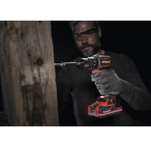 Einhell Akku-Bohrschrauber im Einsatz an einem Holzbalken, geführt von einer Person mit Arbeitshandschuh und Schutzbrille.