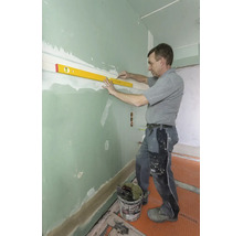 Handwerker nutzt eine Wasserwaage und einen Bleistift, um eine waagerechte Linie an einer grünen Trockenbauwand zu markieren.