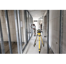 Stabila Rotationslaser auf Stativ auf einer Baustelle für den Innenausbau mit Metallprofilen und zwei Handwerkern.