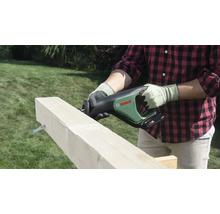 Eine Person schneidet einen Holzbalken mit einer Bosch Akku-Säbelsäge im Garten.