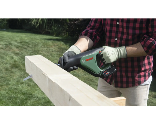 Eine Person schneidet einen Holzbalken mit einer Bosch Akku-Säbelsäge im Garten.