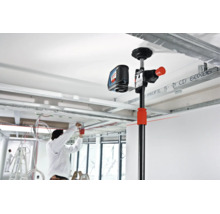 Bosch Baustativ mit montiertem Kreuzlinienlaser bei der Arbeit in einem Innenraum mit Metallständerprofilen an der Decke.