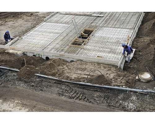 Baustelle mit einer Betonplatte, Bewehrungsstahl und Bauarbeitern bei der Erstellung eines Fundaments.
